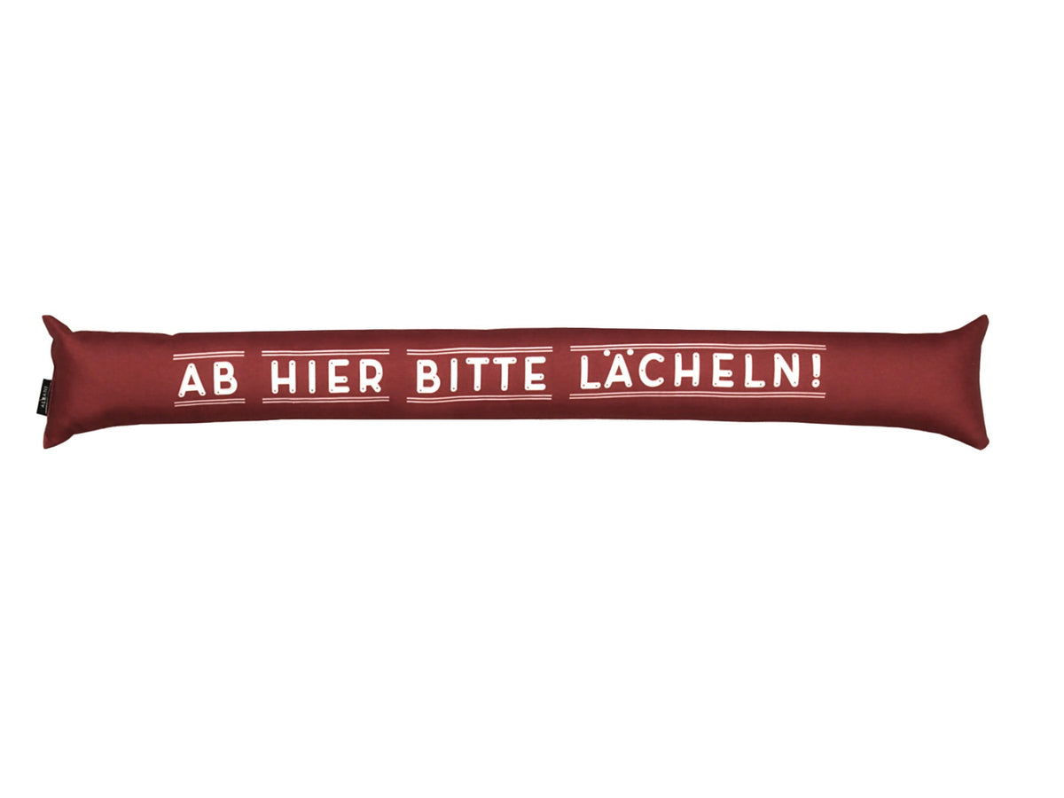 Zugluftstopper rot 10x90cm von Albani mit Spruch 'Ab hier bitte lächeln' für Türen und Fenster